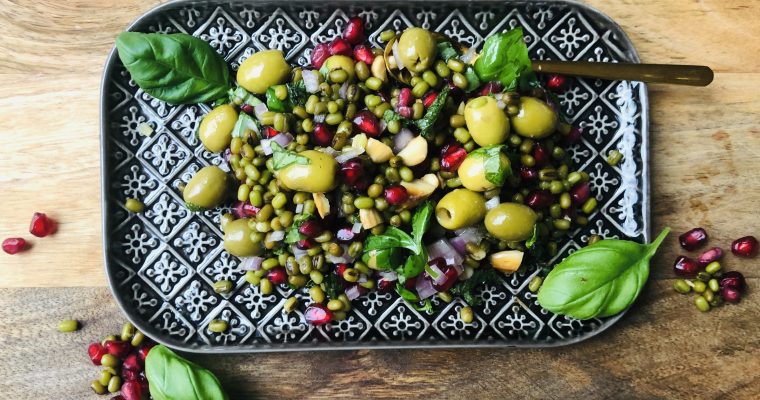 Mungbonensalade met groene olijven, granaatappelpitjes en groene kruiden